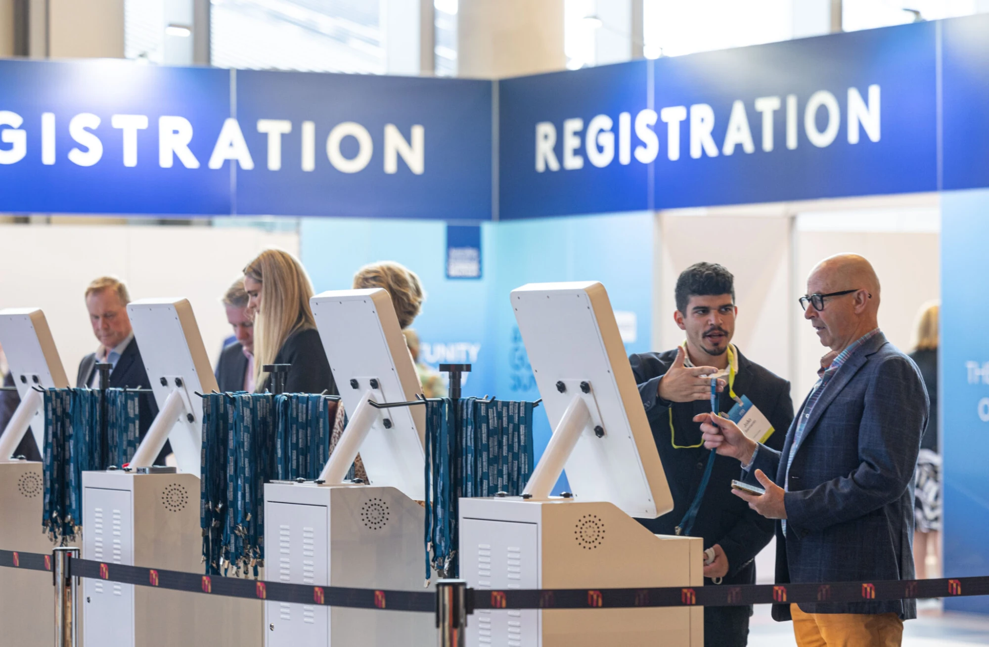Registration counters with self check-in kiosks and lanyards at a conference